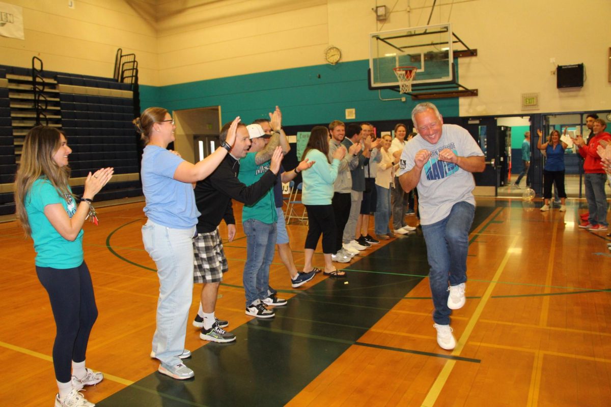Original Raven Ed Rosin, who has taught math at Auburn Riverside since the school opened in 1997, dances through a crowd of teachers during the Raven Walk in the gymnasium last Friday. Rosin is one of seven Ravens who is retiring this year.