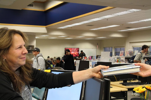 Ms. Gallinatti handing a student a book in the ARHS library; taken by Joseph Davis.
